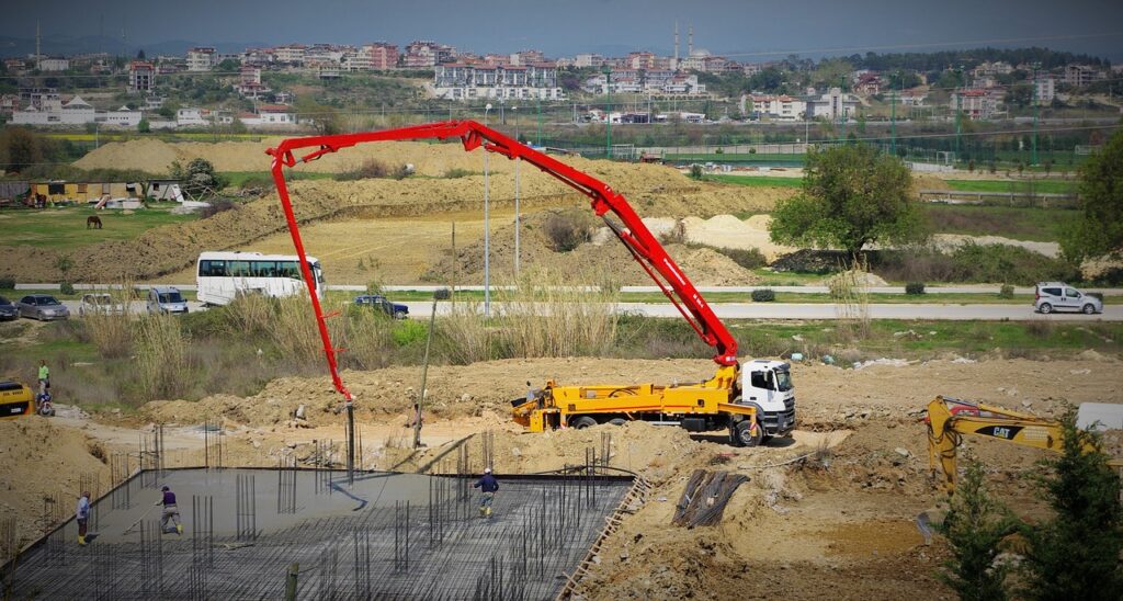 Camion dépliant sa grue sur un chantier pour faciliter l'étalage de la dalle de béton.